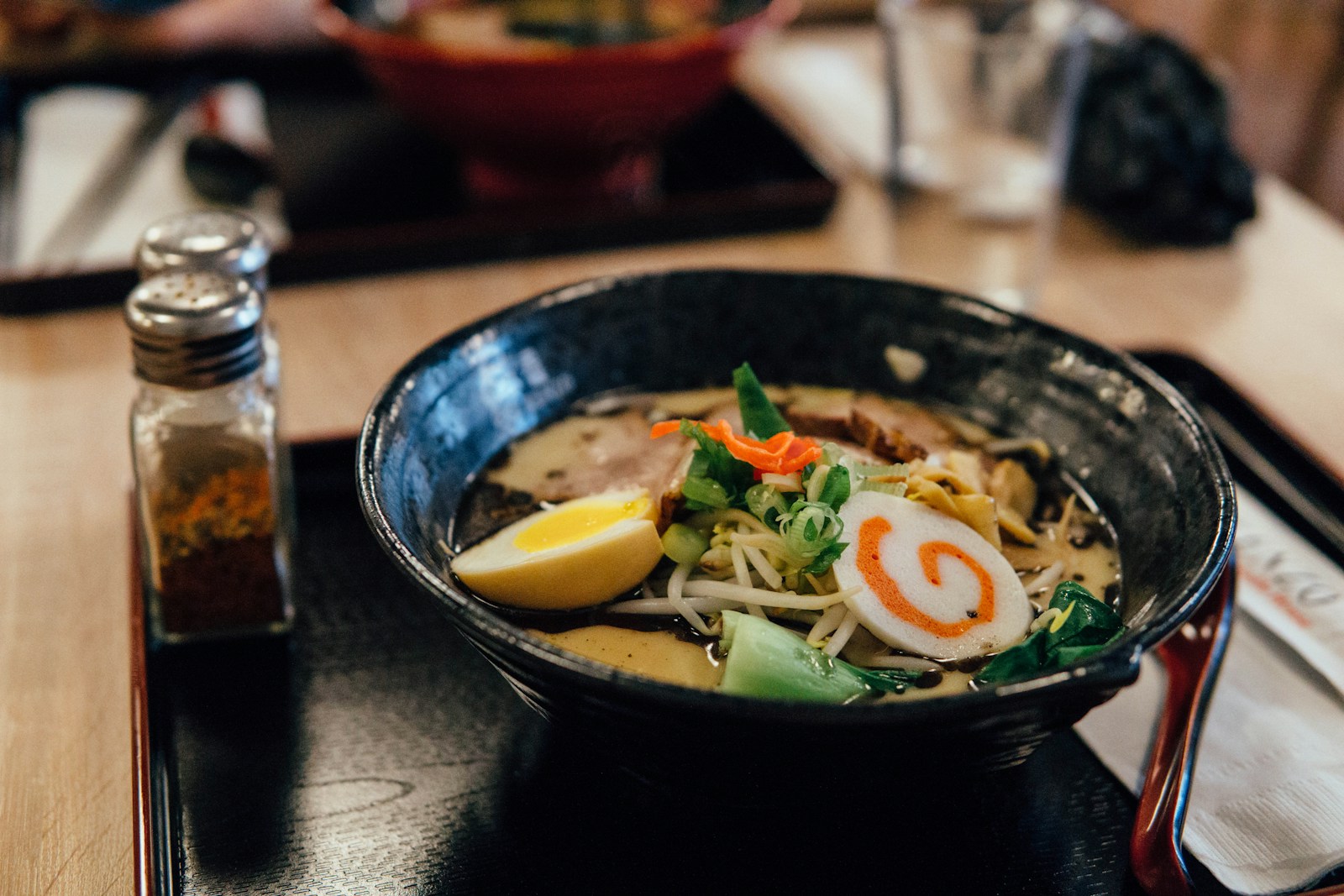 Bát ramen với trứng, rau và nước dùng đặt trên bàn ăn